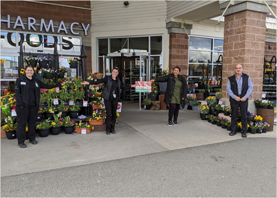 Thrifty Foods employees passing gift cards to customers while physical distancing.