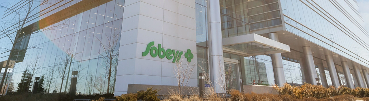 Sobeys corporate office building with glass exterior and landscaped entrance in daylight.